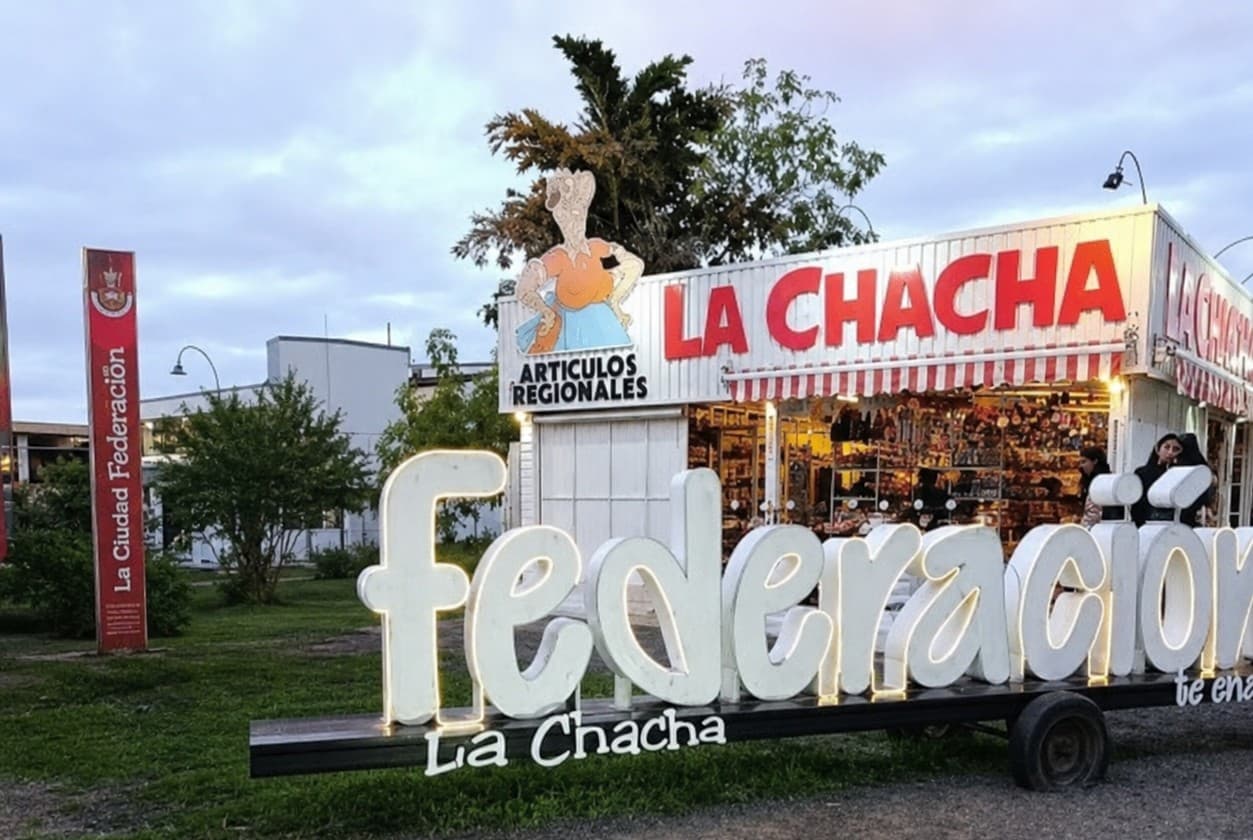 Frente del comercio de artículos regionales La Chacha al atardecer, con las letras iluminadas de Federación delante.